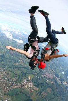 two people doing tricks in the air with their feet up and hands on each other