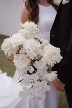 a bride and groom holding a bouquet of white flowers