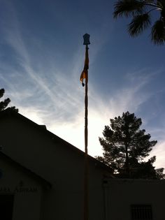 a tall pole with a flag on it in front of a building and sky background