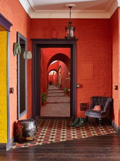 an orange hallway with black and white checkered flooring, red walls and doors