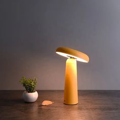 a yellow table lamp sitting next to a potted plant