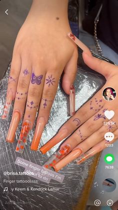 a woman's hands with tattoos on their fingers and nails, all painted orange