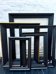 four black frames sitting on top of a wooden floor