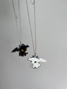 two necklaces with cartoon characters on them hanging from chain links in front of grey background