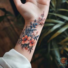 a woman's hand with a flower tattoo on her left wrist and an orange flower in the middle