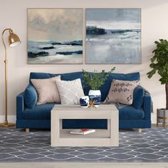 a living room with blue couches and two paintings on the wall above each sofa