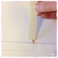 a hand holding a piece of white paper with a small hole in the middle that has been taped to it