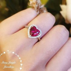 "Hand made 2-carat eq. (8 mm) heart cut lab Ruby engagement ring, with brilliant cut white diamond simulants halo, white gold or rose plated sterling silver, discreetly adjustable band. " Unique on Etsy!  This is a such a romantic ring with a stunning Pigeons blood colour lab Ruby heart shaped centre stone! Great clarity!  Ruby is the most expensive coloured stone every sold in auctions. What matters the most is the colour and transparency as most natural rubies are heavily included, that it is Ruby Heart Ring, July Birthstone Ring, Romantic Rings, Ruby Heart, Ring Ruby, Diamond Heart Ring, Silver Heart Ring, Ruby Engagement Ring, Classic Engagement Rings