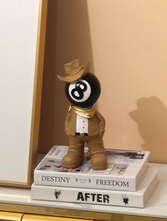 a small black and white toy on top of a stack of books next to a wall