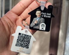 a person holding a house shaped keychain with a qr code attached to it