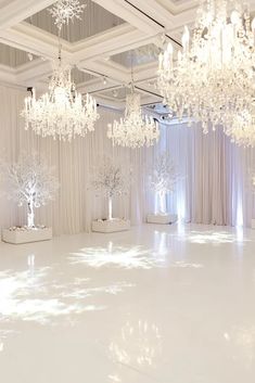 a white dance floor with chandeliers hanging from the ceiling