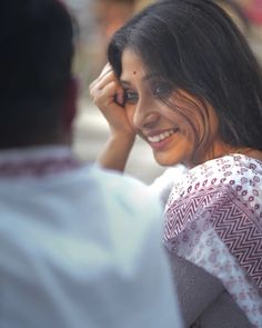 a woman smiles as she holds her hand to her ear