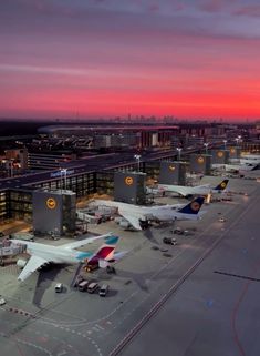 an airport with several planes parked on the tarmac at sunset or sunrise, as seen from above