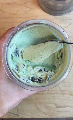 a person holding a spoon in a cup filled with ice cream