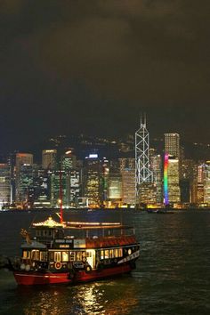 a large boat floating on top of a body of water next to a city at night