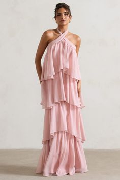 a woman is wearing a pink dress with ruffles