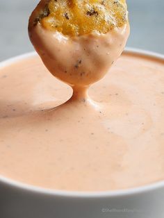 a piece of food is being held up in the air over a bowl of soup