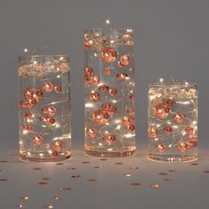 three glass vases with lights in them and some coins around the bottom one is empty