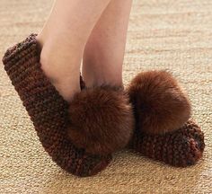 a woman's feet wearing slippers with pom - poms