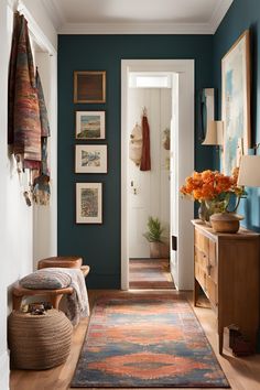 a hallway with blue walls and rugs on the floor, orange flowers in vase