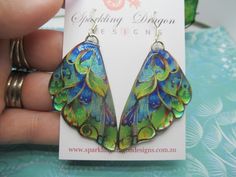 Butterfly Wing Earrings Stained Glass- Fairy Jewellery, Fun Gift for her Statement Present Sparkly Boho Resin with Glitter Finish Boho Butterfly Wing Earrings, Resin with Glitter Finish - Rainbow Butterfly Earrings - Statement Dangle Earrings Oh hi, pretty butterfly! With their whimsical design and iridescent glitter finish, these butterfly wing earrings will send your heart a-flutter. Shimmering with all the colours of the rainbow, they're a beautiful way to accessorise your outfit. Let yo Green Fairy Earrings For Gift, Fairy Style Green Earrings For Gifts, Handmade Green Fantasy Earrings, Blue Green Butterfly, Fairy Jewellery, Fairy Wing Earrings, Shrinky Dink Jewelry, Glass Fairy, Boho Butterfly