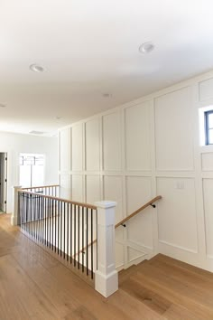 an empty living room with white walls and wood flooring on the bottom half of the stairs