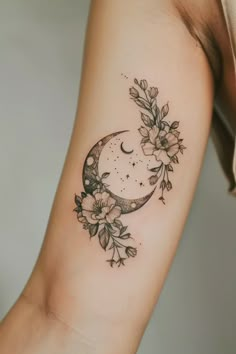 a woman's arm with a crescent and flowers on it