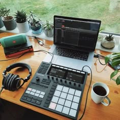 a laptop computer sitting on top of a wooden desk next to headphones and a cup of coffee