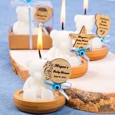 small candles with teddy bears in them on a wooden base and blue ribbon around the edges