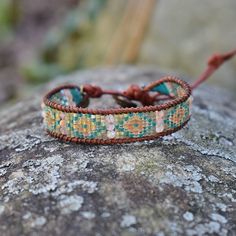 Native American inspired leather wrap bracelet This wrap bracelet is handmade with - Glass beads - Sunstone gemstone beads - Natural brown genuine leather cord - Brown silk cord - Brass button Adjustable with 4 loops to fit the gold metal button. 9in long and .5in wide. Adjustable Multicolor Artisan Wrap Bracelet, Adjustable Artisan Wrap Bracelet For Festivals, Artisan Adjustable Wrap Bracelet For Festivals, Adjustable Artisan Wrap Bracelet For Festival, Bohemian Adjustable Wrap Bracelet With Round Beads, Adjustable Bohemian Wrap Bracelet With Round Beads, Unique Hand-strung Adjustable Friendship Bracelets, Bohemian Adjustable Hand Wrapped Bracelet, Bohemian Hand Wrapped Adjustable Wrap Bracelet