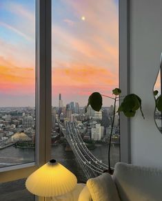 a living room filled with furniture and a large window overlooking a cityscape at sunset