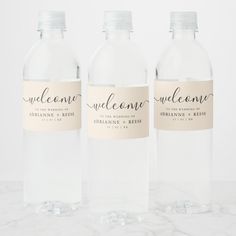 three clear water bottles with labels on them