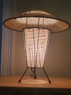 a lamp that is sitting on top of a wooden table next to a wall and window