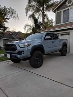 a gray toyota truck parked in front of a house with palm trees and two garage doors