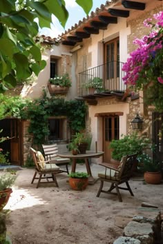 an outdoor patio with chairs, table and potted plants in front of a house