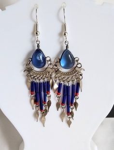 Lovely blue transparent glass Earrings decorated with long strands of blue bead tubes as well as red beads, and finished off with white metal decorations. The teardrop shaped pieces of glass measure 12mm x 8mm.  Fitted with non-allergenic earring hooks. Aztec Earrings, Metal Decorations, Silk Thread Earrings, Thread Earrings, Red Beads, Blue Jewelry, Earring Hooks, Red Bead, Glass Earrings