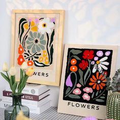 some flowers are sitting on a table next to books and vases with flowers in them