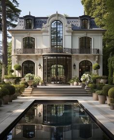 a large white house with lots of windows and plants in front of the pool area