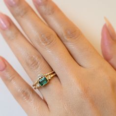 Jennie Kwon has managed to take a straightforward style—the classic solitaire with accent diamonds—and utterly transformed it with the inclusion of a brilliant green emerald at the center. The square band reflects the emerald cute stone, adding an unusual geometric edge to the ring. White diamonds flank the center stone on each side while a beaded bezel setting surrounds all the stones to add a gorgeous dose of texture. Emerald measures 6 mm x 4mm. 14 karat gold with an emerald and two white dia Timeless Emerald Ring With Radiant Cut, 14k Gold Green Diamond Princess Cut Ring, Emerald Ring With Single Diamond For Anniversary, Classic Emerald Ring For Promise, Green Princess Cut Diamond Ring In 14k Gold, Princess Cut Green Diamond Ring In 14k Gold, Timeless Emerald Cut Emerald Promise Ring, Timeless Emerald Gemstone Wedding Ring, Emerald Cut Diamond For May Birthstone Wedding