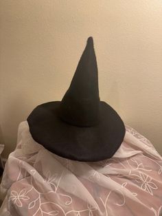 a black witches hat sitting on top of a white cloth covered tablecloth in front of a wall