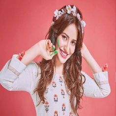 a young woman is smiling and holding her hair in one hand while wearing a flowered headband