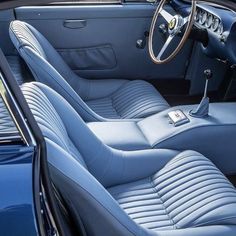 the interior of a classic car with blue leather seats and steering wheel controls, including an automatic