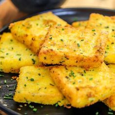 some fried food on a black plate with sprinkles and seasoning around it