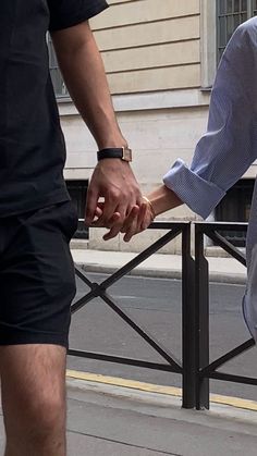 two people holding hands while walking down the street