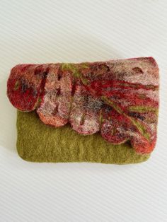 a piece of fabric is sitting on top of a green cloth bag with red and pink flowers