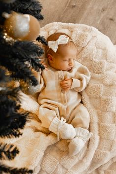 a baby is sleeping on a blanket next to a christmas tree