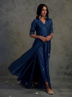 This sapphire blue Chanderi angrakha wrap-around anarkali features exquisite mirror work on the sleeves and beautiful mirror tassels. Paired with stylish joggers, it creates a perfect fusion wear. The ensemble is completed with a Chanderi dupatta embroidered with mirror work along the borders. The bottom is elasticated and has a drawstring for comfort. V Neck Anarkali, Angrakha Anarkali, Blue Anarkali, Silk Kurti Designs, Dapper Outfit, Chanderi Dupatta, Angrakha Style, Blue Kurta, Silk Kurti