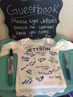 a baby's t - shirt with writing on it and a chalkboard sign that says guestbook please sign jetsons, please to let them know you came down