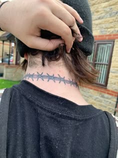 a person with a tattoo on their neck and behind his head is a brick building