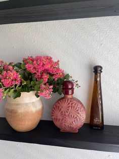 two vases with pink flowers on a shelf